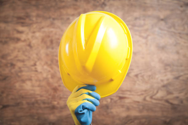 istock Worker hand holding a yellow helmet. 1215867731