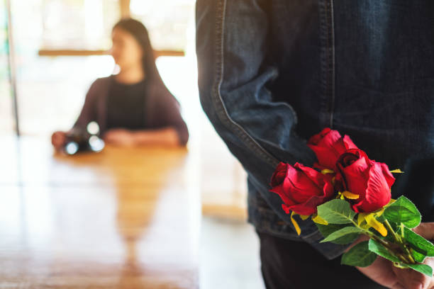 istock A man hiding red roses bouquet on his back to surprise girlfriend 1215867785