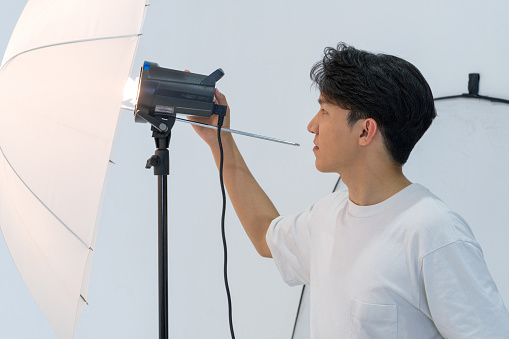Asian photographers are adjusting the brightness of lights for shooting fashion models in the studio.