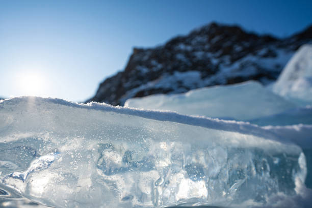 The icy beauty of ice cube, unusual shapes. Closeup crystal clear ice cube that covered with white snow. Lake Baikal, Russia