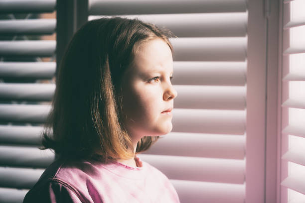 istock Young Girl Views The World Through The Blinds 1215872627