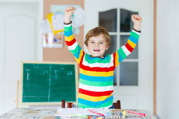 istock Hard-working happy school kid boy making homework during quarantine time from corona pandemic disease. Healthy child writing with pen, staying at home. Homeschooling concept 1215873009