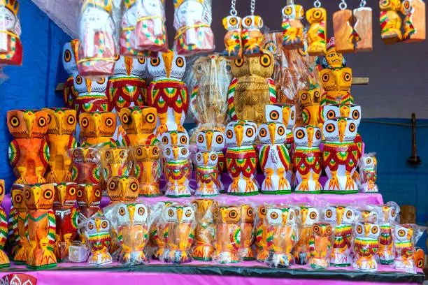 A collection of colorful handmade traditional wooden owl sculpture and toys are displayed for selling in handicraft fair.