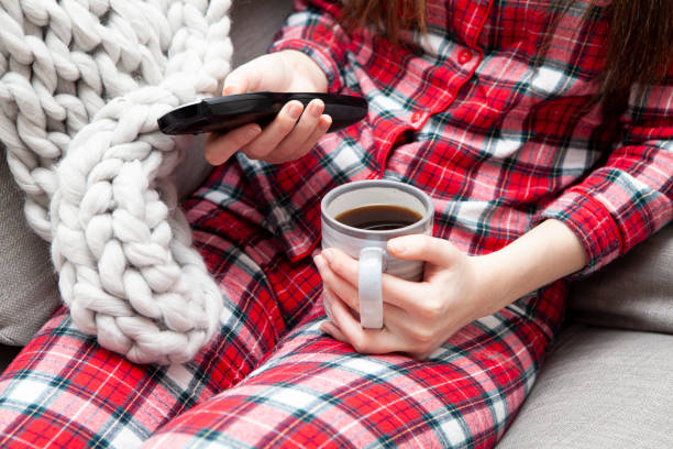 istock Hands holding coffee mug and tv remote 1215875864