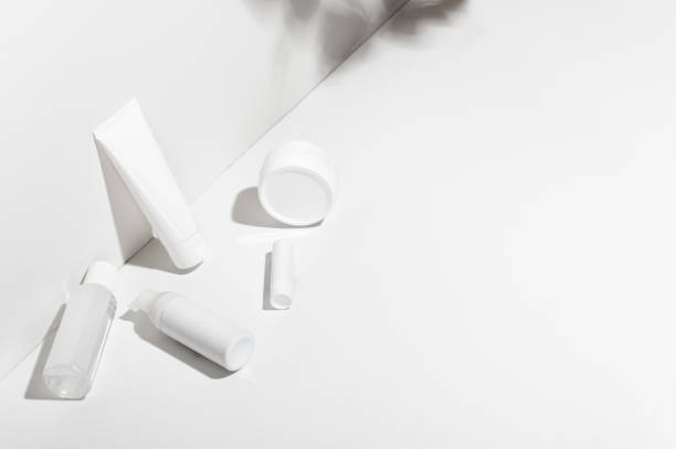 Fallen tubes on white surface. Body lotion, cream, lipstick and spray. Unbranded mockup style. Copy space in right side. Wellness and professional skincare concept
