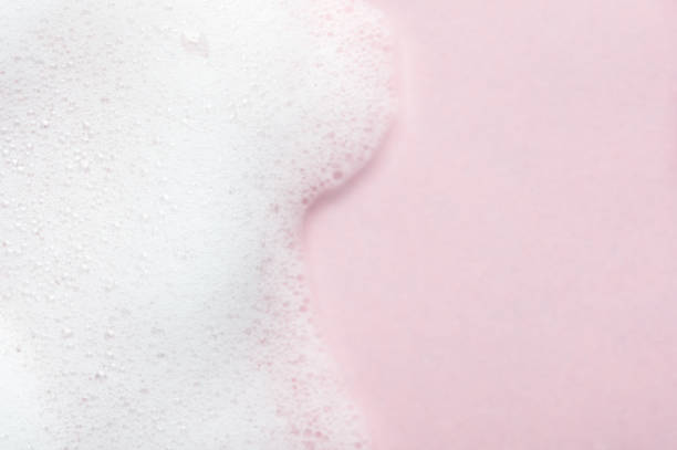 schuimende vloeistof op roze achtergrond. de schuimachtergrond van de cosmetica met exemplaarruimte in juiste kant. cosmetisch product monster van mousse, shampoo of zeep. huidverzorging, cosmetica en schoonheidsconcept - schuim stockfoto's en -beelden