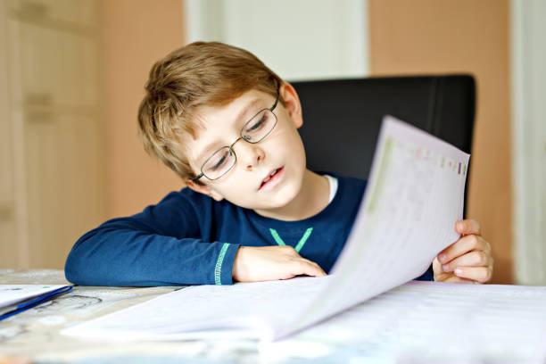 istock Hard-working happy school kid boy making homework during quarantine time from corona pandemic disease. Healthy child writing with pen, staying at home. Homeschooling concept 1215879079
