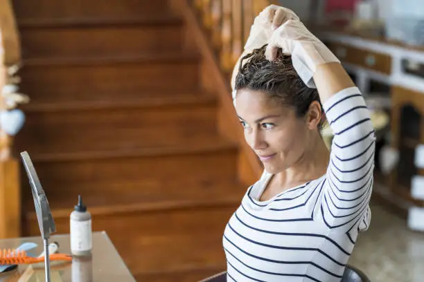 Photo of Home made hair dye at home for beauty young caucasian woman looking at the mirror - stay at home concept for coronavirus emergency worldwide pandemic contagion