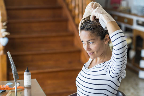 corantes de cabelo caseiros em casa para beleza jovem mulher branca olhando para o espelho - fique em casa conceito para emergência coronavírus em todo o mundo contágio pandemia - tinge - fotografias e filmes do acervo