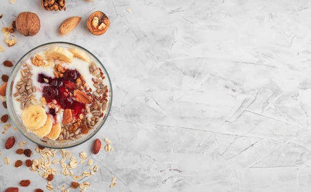 Healthy breakfast concept. Yogurt with granola, cherry jam and nuts in a cup on a gray background. Ingredients for breakfast on the table. Top view, horizontal orientation, copy space. stock photo