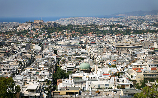 Aerial view over the city of Athens towards the mediterranean sea with the famous ancient greek Athens Acropolis in the center. Athens, Greece.