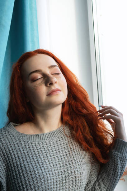 istock Woman near window, eyes closed. 1215887966