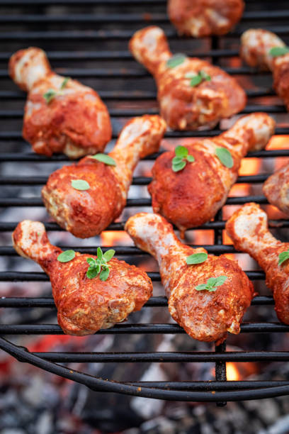 istock Raw and spicy chicken legs with spices on grill 1215888560