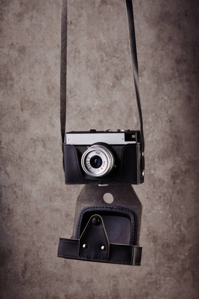 vintage analogowy dalmierz film kamery w skórzanej obudowie wiszące przed betonową teksturą ściany jako tło - rangefinder camera zdjęcia i obrazy z banku zdjęć