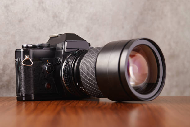 istock Single-lens reflex professional camera on wooden table and concrete wall as a background 1215891804