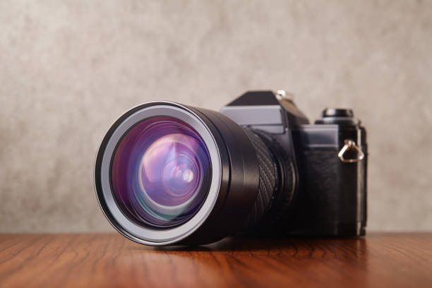istock Single-lens reflex professional camera on wooden table and concrete wall as a background 1215891805