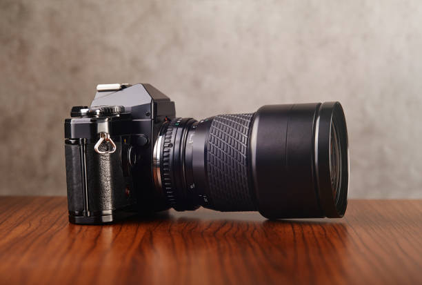Single-lens reflex professional camera on wooden table and concrete wall as a background
