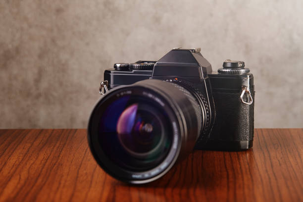 istock Single-lens reflex professional camera on wooden table and concrete wall as a background 1215891930