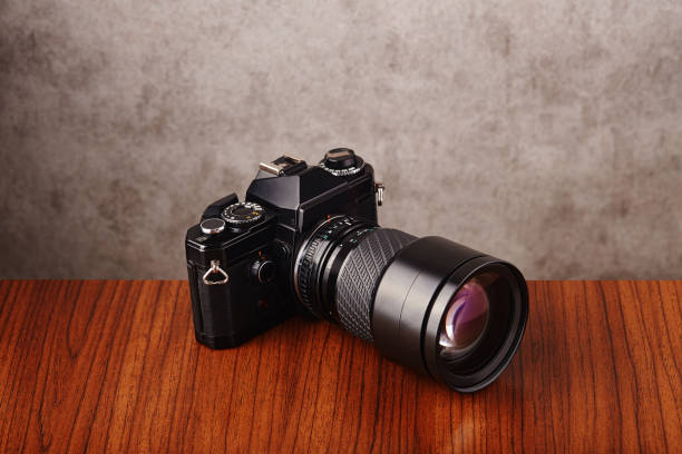 istock Single-lens reflex professional camera on wooden table and concrete wall as a background 1215892016