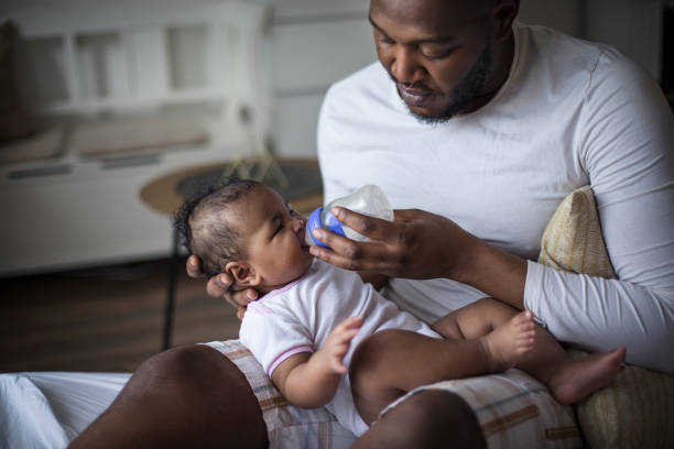 Somebody's hungry. Somebody's hungry. African American father feeding his daughter. african father stock pictures, royalty-free photos & images