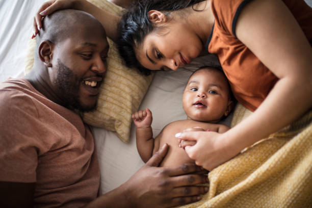 Family bonding time. Family bonding time. African American parents with daughter on bed. real life stock pictures, royalty-free photos & images