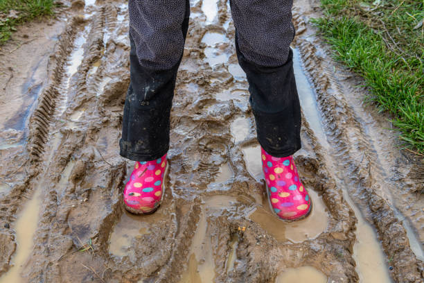 istock child walking in mud with multicolored boots 1215892682