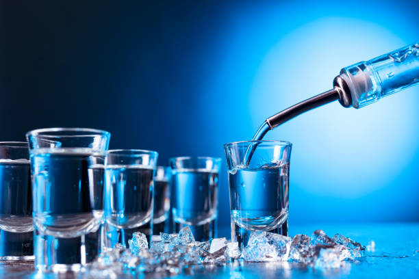 el vodka se vierte en un vaso iluminado con luz de fondo azul. - 3894 fotografías e imágenes de stock