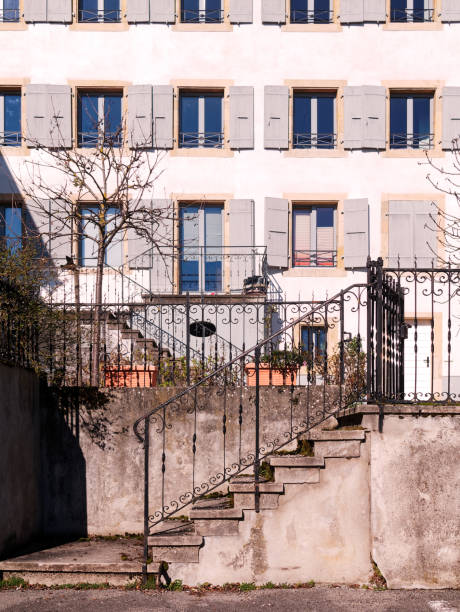 verwitterte betontreppe mit schmiedeeisernen handläufen und gebäudefassade mit fenstern mit holzläden. - switzerland tourism wall window stock-fotos und bilder