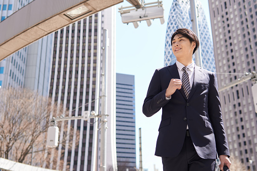 A Japanese male businessman jumps in the office district.