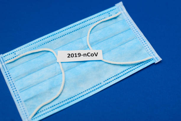 istock Coronavirus 2019-nCoV printed on paper with a respiratory mask on a blue background. 1215901083