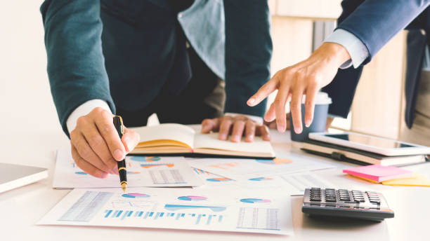 istock Midsection Of Colleagues Discussing Report On Desk In Office 1215903314