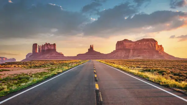 Endless highway wide angle Panoramic View under colorful twilight summer sky towards the famous Monument Valley Buttes in Utah. Looking south on U.S. Route - Highway 163 from north of the Arizona–Utah border. Arizona - Utah, USA, North America.