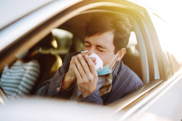 istock Young man coughing and sneezing into a handkerchief 1215904086