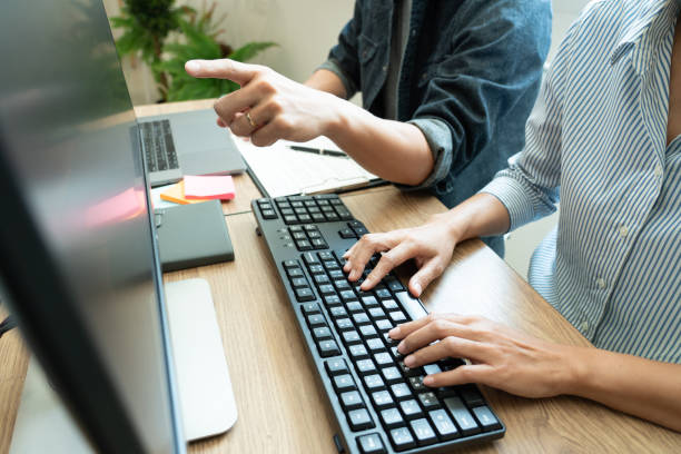istock Midsection Of Colleagues Discussing Over Computer In Office 1215904529
