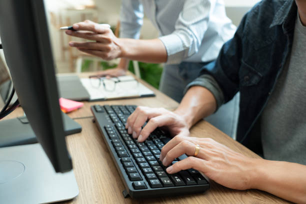 istock Midsection Of Colleagues Discussing Over Computer In Office 1215904778