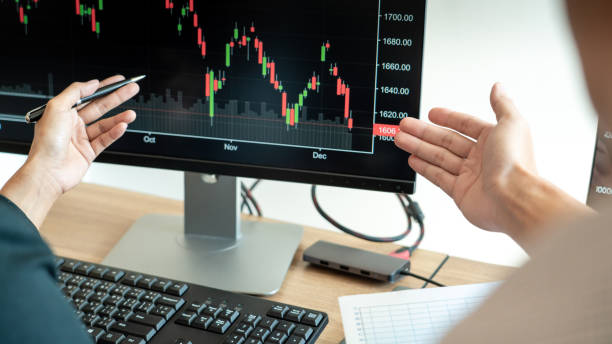 istock Cropped Hands Of Colleagues Analyzing Stock Market Data Over Computer In Office 1215905000
