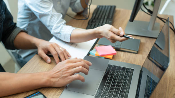 istock Midsection Of Colleagues Discussing Over Laptop In Office 1215907052