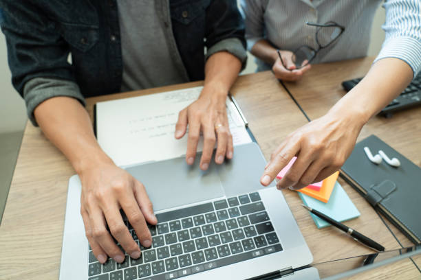 istock Midsection Of Colleagues Discussing Over Laptop In Office 1215907116
