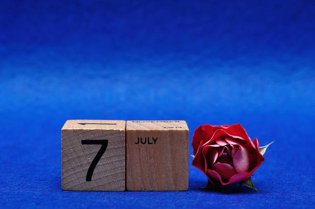 istock 7 July on wooden blocks with a red rose on a blue background 1215907536