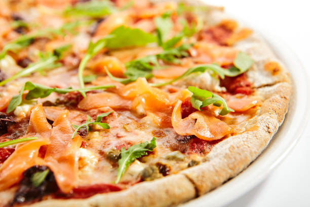 нарезанная пицца с лососем, оливками каламаты и вялеными помидорами - calamata olive стоковые фото и изображения