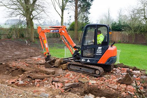 Buckingham, UK - February 13, 2016. Digger, bulldozer clearing rubble in preparation for hard landscaping a garden in UK