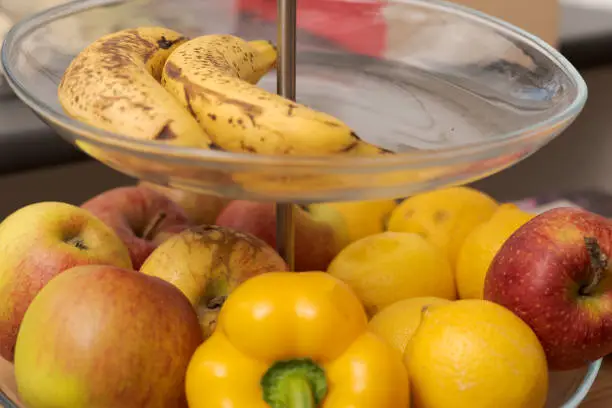Various fresh fruit and vegetables lying on glass etagere, bell pepper, apples, banana and lemon