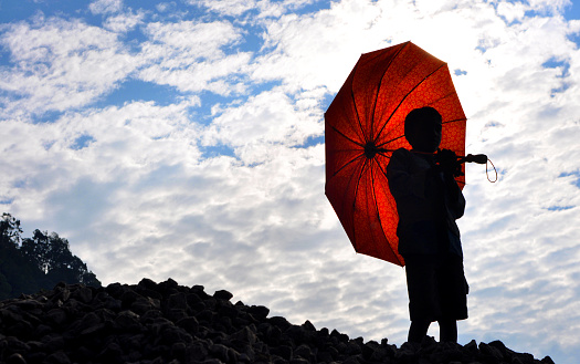 Unrecognized boy stands in front of clouds