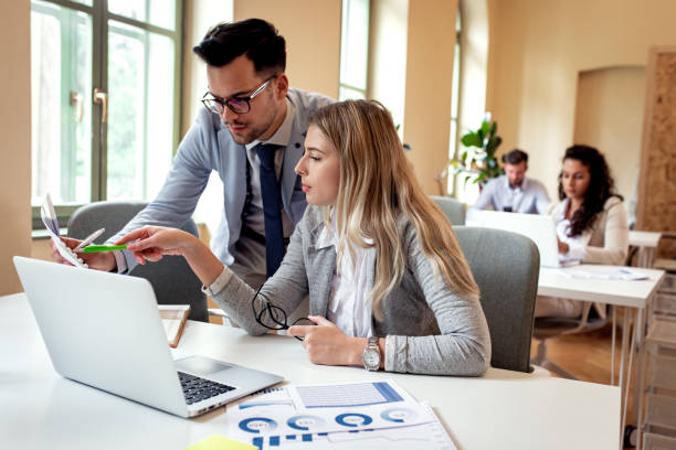 istock Two coworkers working together using laptop in office. 1215913951