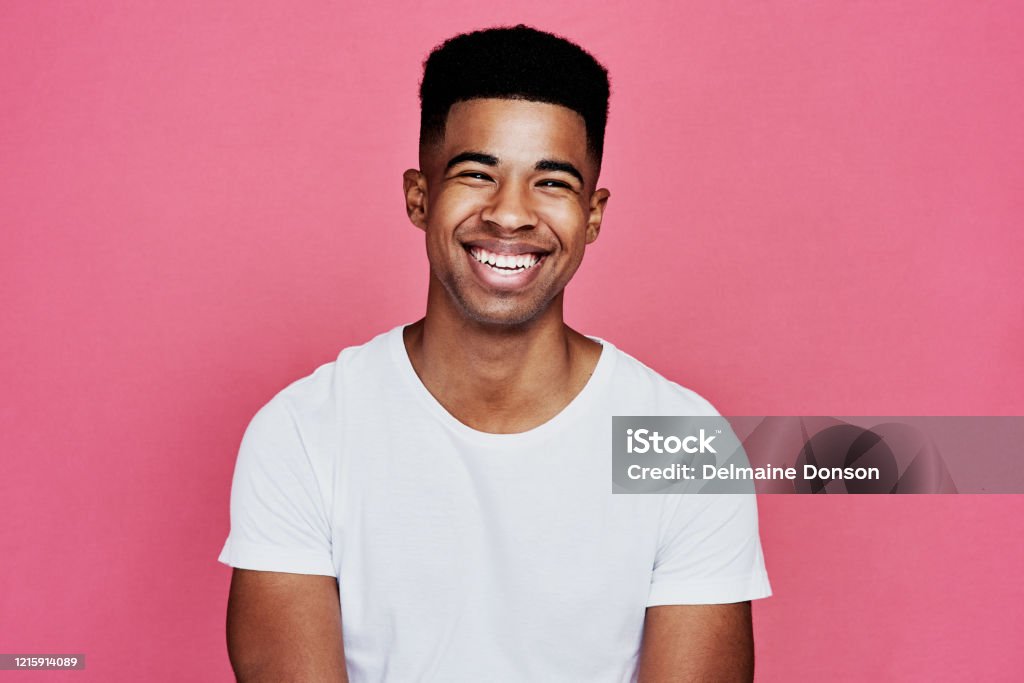 Nothing but smiles here Cropped portrait of a handsome young man standing alone against a pink background in the studio Young Men Stock Photo