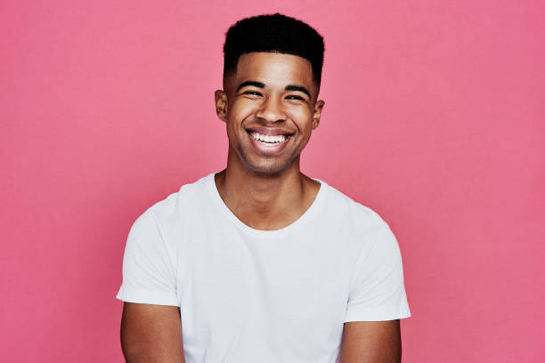 Nothing but smiles here Cropped portrait of a handsome young man standing alone against a pink background in the studio one young man only photos stock pictures, royalty-free photos & images
