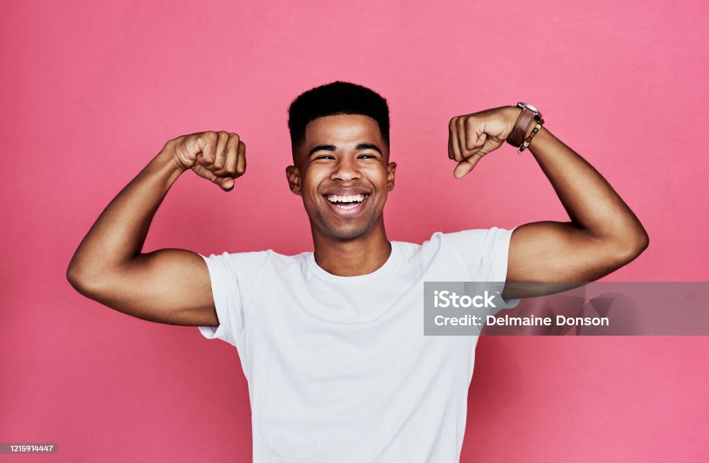 Are you checking me out? Cropped portrait of a handsome young man standing alone and flexing his biceps against a pink background in the studio Men Stock Photo