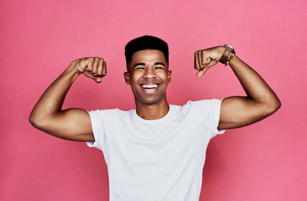 Are you checking me out? Cropped portrait of a handsome young man standing alone and flexing his biceps against a pink background in the studio bicep stock pictures, royalty-free photos & images