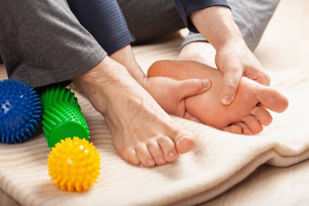 uomo che fa auto massaggio correzione piede piatto a casa - reflexology human foot physical therapy massaging foto e immagini stock