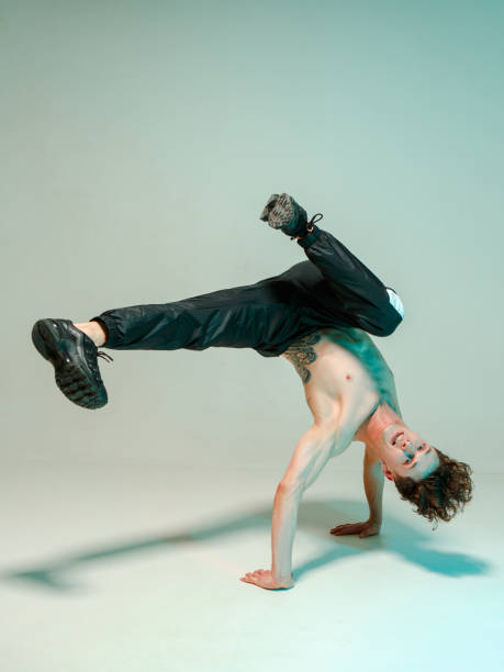 istock A young graceful guy is dancing a break dance on the floor without a t-shirt. Complex tricks. Body with tattoos. 1215915957